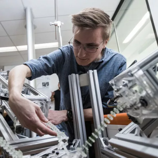 Student adjusts mechanical parts in a robotics lab