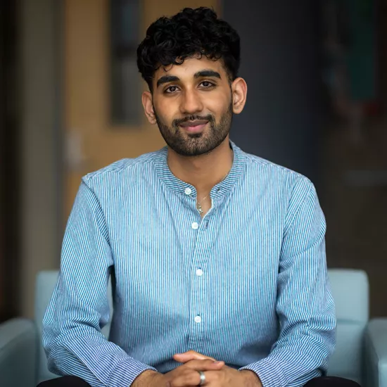 Salik Qureshi sits with his hands clasped in a blue armchair.